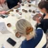 Participants concentrés autour d’une table lors d’un atelier de création de bijoux à Toulouse.