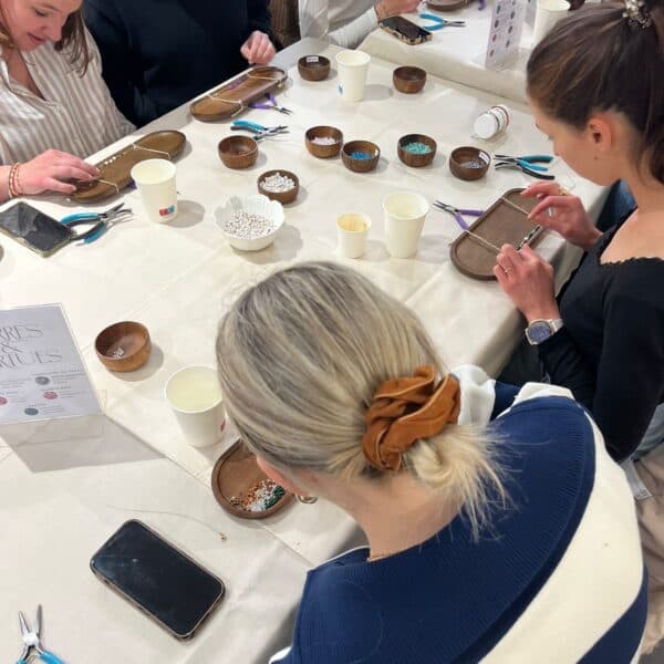 Participants concentrés autour d’une table lors d’un atelier de création de bijoux à Toulouse.