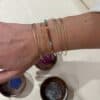 Poignet orné de plusieurs bracelets dorés et d’un bijou en perles colorées fabriqués à l’atelier.